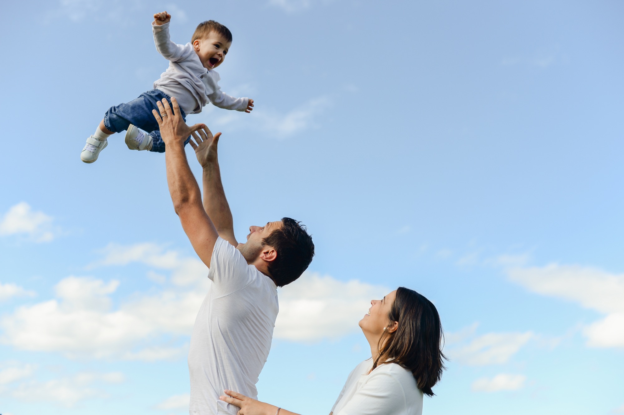 Papa qui lance son enfant dans les airs, ciel bleu