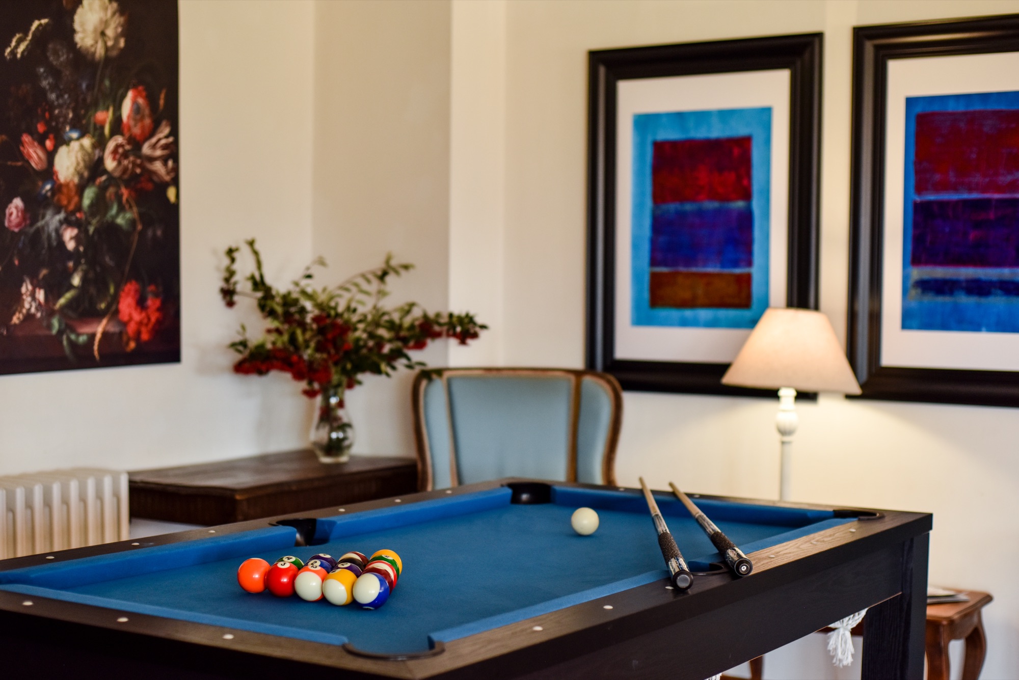 Salle de billard avec tableaux colorés et bouquet de fleurs