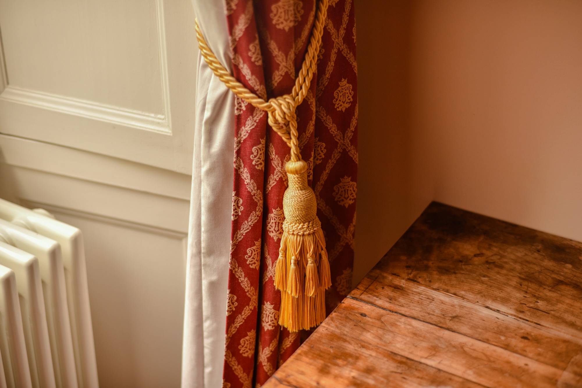 Détail d'un embrasse de rideau doré sur parquet ancien