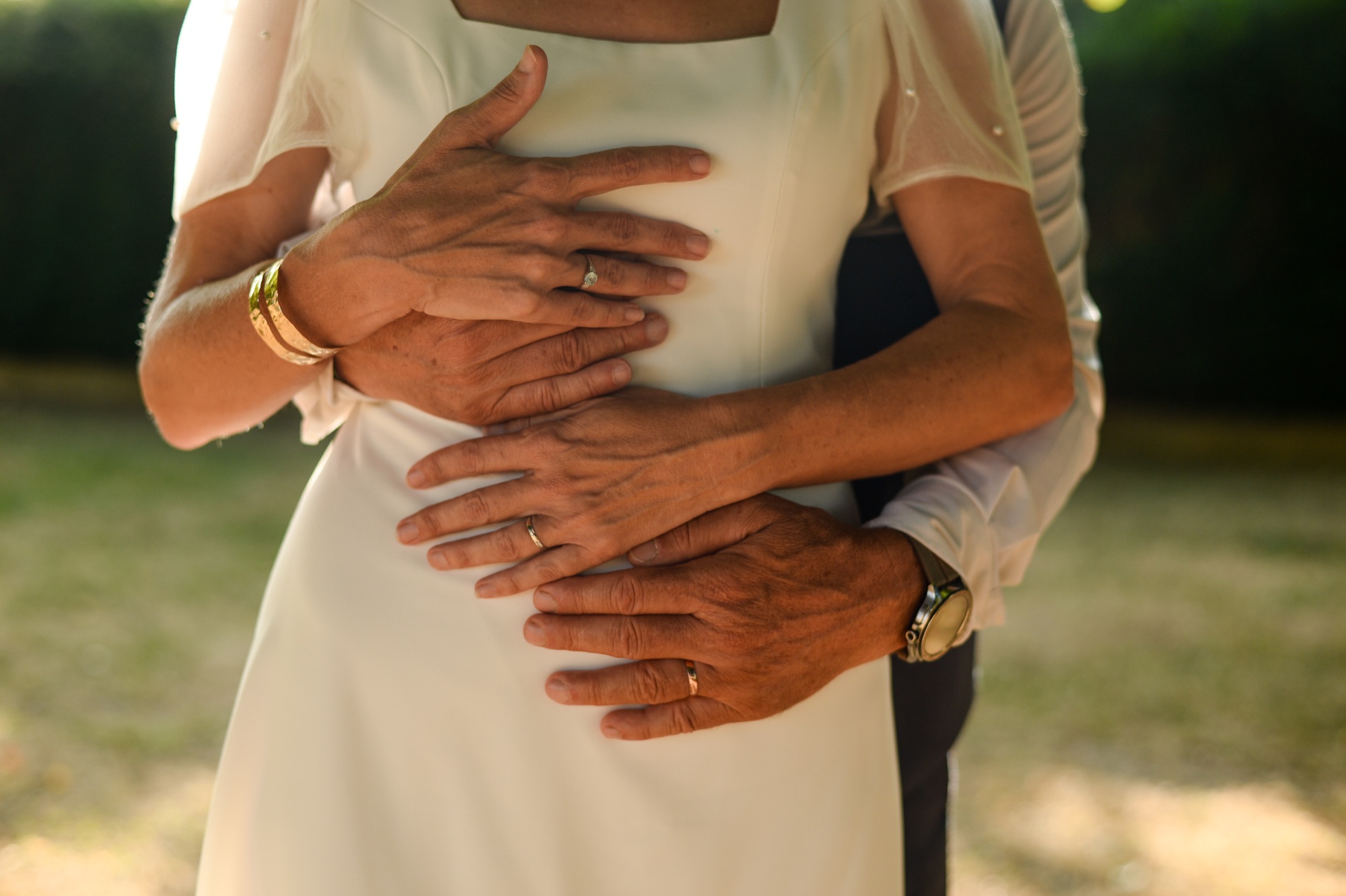 Mains du couple enlacées avec les alliances